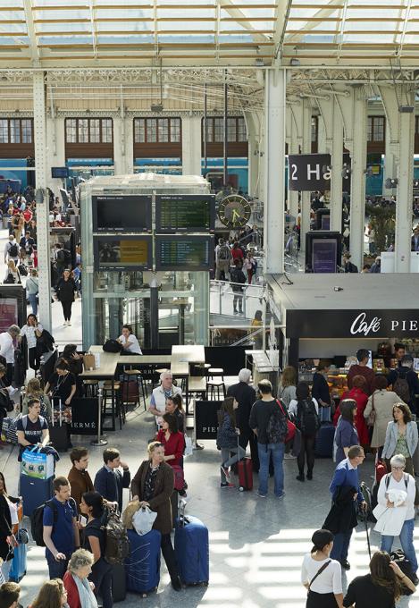 Hall intérieur d&#039;une gare avec des voyageurs attendant leur train